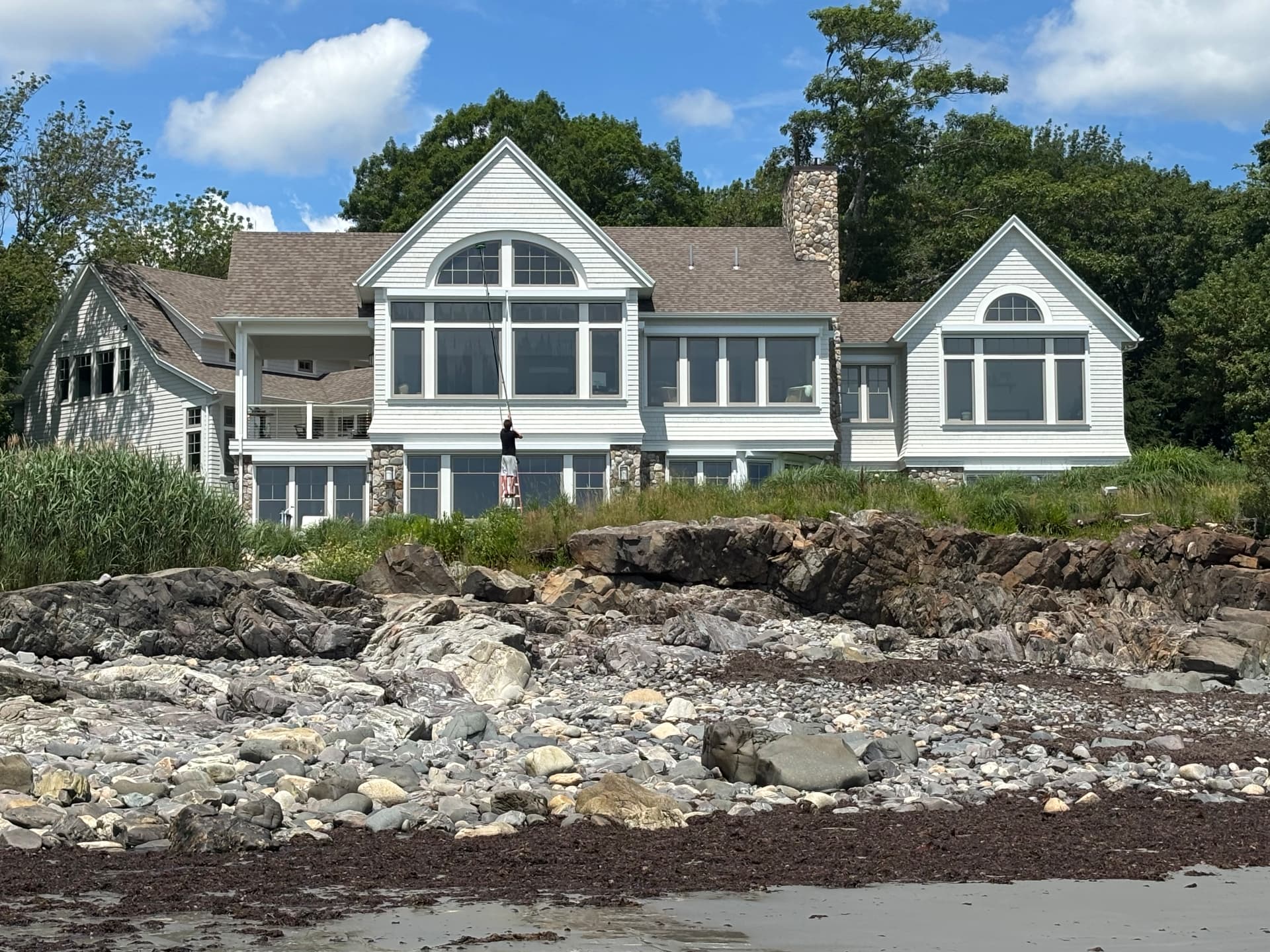 Large coastal home with shingle siding and manicured lawn at sunset